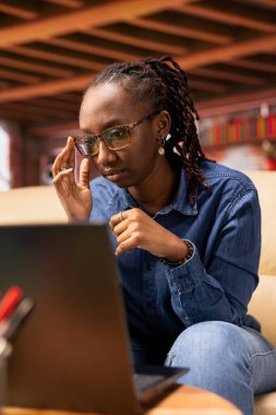 Teknoloji meraklısı kullanıcı yeni bir yazılımı test etmek, yeni dijital araçları yönlendirmek ve sanal görevleri yönetmek için kablosuz bir dizüstü bilgisayar üzerinde çalışıyor. Evinden, oturma odasından birbirine bağlı ve üretken bir yaşam tarzı..