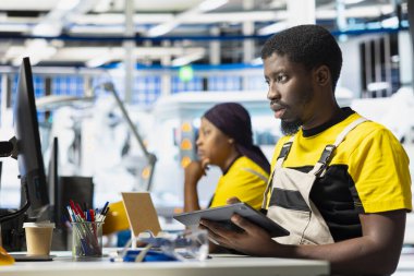 Fotovoltaik fabrikası teknisyeni tablet üzerindeki güneş modülleri için CAD teknik çizimleri inceleyerek montaj sürecini inceliyor. Çalışan aygıt üzerinde güneş paneli tasarımları geliştiriyor.