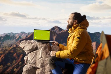 Trekker, sakin dağ manzarası ve açık gökyüzünün macerayı ve azmi simgelediği izole edilmiş taklit ekranın yanındaki panoramik manzarayı alıyor. Teknolojik seyahat tutkusu.