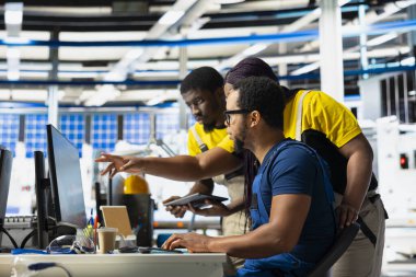 Bir grup siyah çalışan tesisteki güneş pillerinin üretim sürecini inceliyor, üretim hattı için kalite kontrolü yapıyorlar. Yenilenebilir enerji endüstrisi üzerinde çalışan mühendisler.