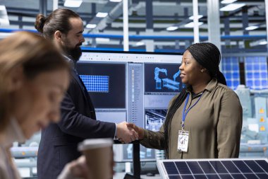 Yönetici yatırımcıyla el sıkışıyor, başarılı güneş panelleri materyal sunumundan sonra finansman sağlıyor. İş adamları verimli bir toplantıdan sonra sanayi bölgesinde tokalaşıyorlar