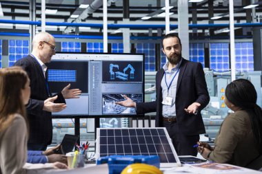 Yatırımcılar için satış sunumu yapan fabrika yöneticileri güneş paneli çözümleri gösteriyorlar. Endüstriyel fabrika yönetimi yenilenebilir enerji pazarında ürün yenilikleri ve rekabetçi avantajlar sergiliyor