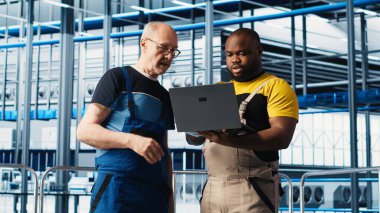 Akıllı fotovoltaik fabrikasındaki kıdemli mühendis stajerle konuşuyor, sistem performans ölçümlerini gösteriyor. Deneyimli güneş panelleri enerji üretimini takip eden yeni stajyer ve kamera A 'ya rehberlik ediyor.
