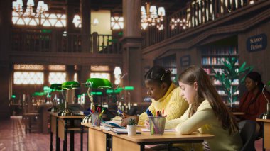 Çeşitli sınıf arkadaşları kütüphanede sınıf ödevlerini birlikte yapıyor, iyi notlar almak için çok çalışıyorlar. Akademik materyallerle ödevlerini yapmaya odaklanmış liseli kızlar. Kamera A.