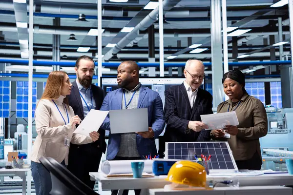 Yatırımcılar ve fabrika yöneticileri belgeleri inceliyor, sürdürülebilir enerji ekipmanı üretim genişlemesi stratejilerini analiz ediyorlar. Üretim fabrikası ekibi işbirliği yapıyor.