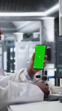 Biolab masasında laboratuvar teknisyeni olan kimya uzmanı tarafından kullanılan akıllı telefondaki dikey video görüntüleme ekranı, genetik araştırma, nanoteknoloji ve tıbbi keşif ve yenilik verileri üzerine odaklanmıştır.