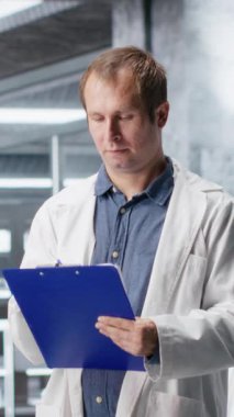 Dikey Video Biyoloji uzmanı bir araştırma çalışmasında deney verilerine odaklanıyor. Laboratuvar ekipmanları ve kimyasal testler biyokimya, genetik ve biyomühendisliği vurguluyor. Bilim adamı işi. Kamera.