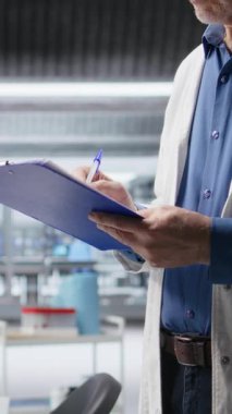 Araştırma çalışması için panoya yazılan Dikey Video Adam el yazısı notları bir kimya laboratuvarında, biyokimya, nanoteknoloji ve tanı için bir deney yürüten bir araştırmacıyla sonuçlanır. Kamera A.