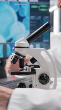 Laboratuvarda araştırma çalışması için mikroskop altında numune tepsisi inceleyen Dikey Video Çalışanı hücresel araştırmayı kaydırıyor ve genetik araştırmayı destekliyor. Sağlık hizmetleri için gelişmiş analiz