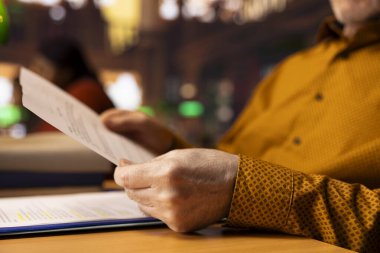 Kıdemli adam, akademik materyal ve kitaplarla çevrili, kütüphanede öğrenim gören olgun bir öğrenci. Öğrenci, yaşlılıkta zekayı benimsemeye ve araştırma yapmaya odaklanır..