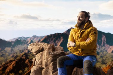 Yürüyüş yolcusu, tepedeki panoramik dağ manzarasına, sonsuz gökyüzüne ve kayalık tepelere hayranlık duymak için ara verir. Zihinsel berraklık için nefes kesici bir zemin oluşturur. Dışarıdaki maceracı..