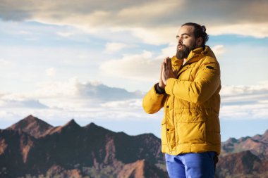 Huzurlu bir kâşif, stres atmak için meditasyon yapıyor. Dağın tepesinde rahatlık ve denge için dinleniyor. Genç gezgin, dikkat çekmek için meditasyon yapıyor..