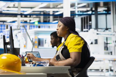 Fotovoltaik fabrikası teknisyeni güneş paneli üretim hattının performans testini yapmak için dizüstü bilgisayar kullanıyor. Maliyet düşüşü için sürdürülebilir güneş enerjisi ayarlarını geliştiren kadın.