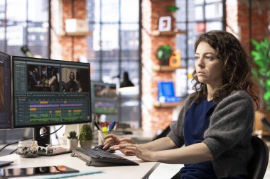 Kadın video yapımcısı bir film montaj projesi üzerinde çalışıyor, çift monitörlü birden fazla iş yapıyor. Kadın çekim editörü sinematik yaratıcı süreci başlatıyor, film düzenleme endüstrisi.