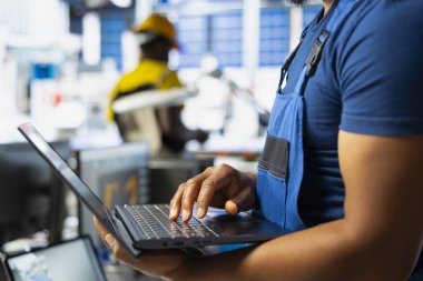 Black engineer running diagnostic checks on solar panel assembly software, optimizing the production process and solar cells for alternative energy. Industrial factory finetuning.