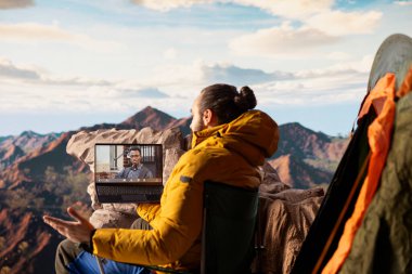 Macera Avcısı 'nın her yerde interneti var ve video görüşmelerini kullanıyor. Dağın tepesinde iş arkadaşlarıyla sohbet ediyor. Teknolojik saplantısı ve bağımlılığı olan bir yürüyüşçü..