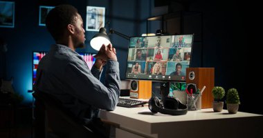 Siyah adam internet görüntülü konferansta bir grup bireyle buluşuyor, teknolojiyi sanal iletişim için kullanıyor. Uzaktan çalışan serbest çalışan, rahat bir evde online toplantılar ya da dersler yapan biri. Kamera A.