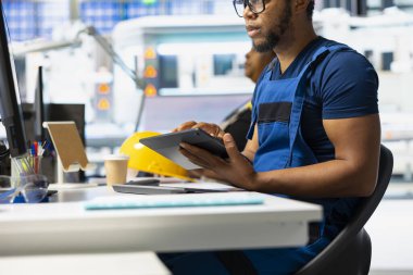 Güneş paneli montaj hattını denetlemek için tablet kullanan erkek mühendis, üretim tesisinde sürdürülebilir alternatif enerji sağlıyor. Fabrikadaki fotovoltaik sistem üretiminde sorun var.