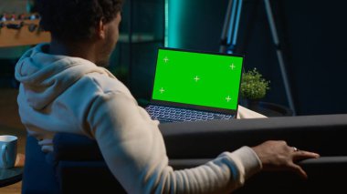 Mutlu genç adam evinde izole edilmiş fotokopi odasını kullanıyor, modern oturma odasında, neon ışıkları ve son moda mobilyalarla süslenmiş olarak dinleniyor. Aletleri olan bir erkek. Kamera A.