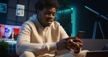 Genç siyahi yetişkin oturma odasından Webinar kursuna katılıyor ve profesörle video bağlantısı yoluyla buluşuyor. Uzaktan yüksek lisans için sıkı çalışan bir adam, telekonferans. Kamera B.