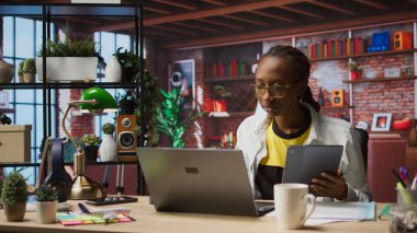 Tabletteki sosyal medyaya bakmak için işten izin alan bir kadın. Apartman ofisindeki uzaktan çalışan, sosyal ağ uygulamasını cihazda kullanmak için görevleri durduran, kamera A