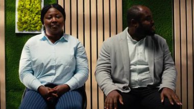 İnsan Kaynakları asistanı, iş arayan, iş görüşmesi bürokrasisi ile ilgili belgeleri ve özgeçmişleri düzenleyen arabalara kayıt formlarını getiriyor. Detayları yazıyor. Kamera B.