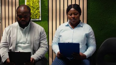 Endişeli siyahi kadın iş arayan insan kaynakları ofisinden görüşmeye başlamak için çağrılıyor, tartışmayı bekliyor ve ofiste beklenti sergiliyor. İşe alım sürecine hazırlanan insanlar. Kamera A.