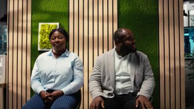 İnsan Kaynakları asistanı, iş arayan, iş görüşmesi bürokrasisi ile ilgili belgeleri ve özgeçmişleri düzenleyen arabalara kayıt formlarını getiriyor. Detayları yazıyor. Kamera A.