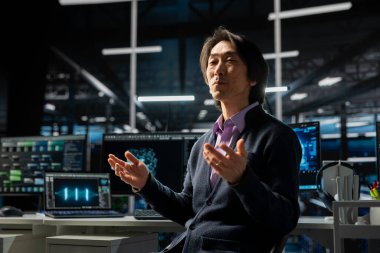 Sunucu odasında bilgisayar bilimci altyapı teşhislerini incelemek için aygıt kullanıyor. Yüksek teknoloji veri merkezinde Asyalı kıdemli programcı sistem uptime 'ı korumak için performans verilerini analiz ediyor