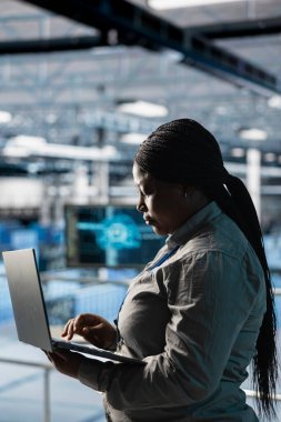 Veri merkezindeki kadın mühendis, yapay zeka görevleri için özelleştirilmiş donanımı yapılandırmak için dizüstü bilgisayar kullanıyor. Platformlarda bakım yapan kadın yapay zeka hesaplaması için yük dengeleme yapıyor.