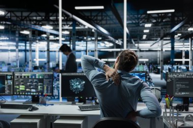 Yorgun veri merkezi yazılım geliştiricisi AI LLM asistan kullanırken gerilimi azaltmak için esniyor. Sunucu odası bilişim uzmanı masajı, yapay zeka sohbet robotuyla bilgisayar kodlamasında saatler geçirdikten sonra geri döndü