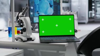 Bilgisayarlı dizüstü bilgisayar boş laboratuarda, araştırma araçları, kan örnekleri ve kavanozlarla birlikte. Klinik kurulum biyoteknolojiyi ve test için kimya ekipmanlarını yansıtıyor.