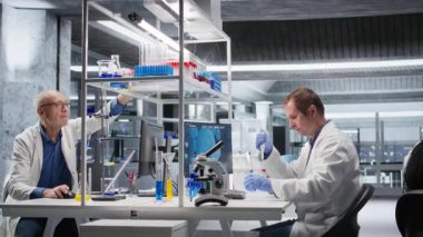 Klinik laboratuar araştırmacısı çözümü pipet ve kavanozlarla hazırlıyor, genetik araştırma ve biyoteknoloji moleküler analizi için maddeyi karıştırıyor. İleri düzey araştırma yapıyorum. Kamera A.