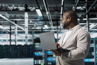 Veri merkezindeki programcı dizüstü bilgisayar kullanıyor, hata kayıtlarını okuyor, donanım ömrünü uzatmak ve devre dışı kalmaktan kaçınmak için kontrol yapıyor. Sunucu merkezi işyeri çalışanı not defteri kullanarak altyapı platformlarını izliyor