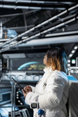 Uzay gemisindeki kadın astronot bilim adamı tablet kullanarak bilimsel deneyler yapıyor. Uzay gemisinde kozmonot ekipmanı giyen kadın araştırmacı cihaz kullanarak araştırma yapıyor.