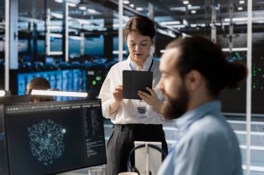 Depolama dizilerini güncellemek için tablet kullanarak veri merkezindeki yönetici ağ sanal yapılandırmasını ayarlar. Sunucu odasındaki kadın ayarları doğrulamak için aygıt kullanıyor, istikrarlı performansı sürdürüyor