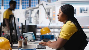 Siyah teknisyenlerden oluşan bir ekip fabrikada üretilen güneş panellerini inceliyor ve üretim hattı için kalite kontrolü yapıyor. Yenilenebilir enerji endüstrisi üzerinde çalışan mühendisler. Kamera A.