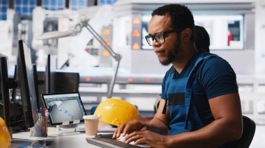 Güneş enerjisi uzmanı, araştırma ve yenilik odaklı çevre dostu fabrikada tasarım modellerini güncelliyor. Erkek işçi dijital sistemler kullanarak sürdürülebilir endüstriyel büyümeyi destekliyor. Kamera A.