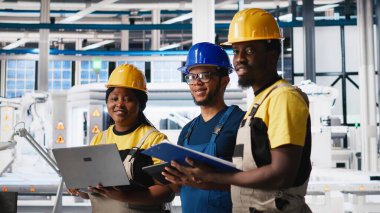 Güneş panelleri fabrikasında çalışan bir grup siyah işçi cihaz ve belgelerdeki verileri inceliyor. Fotovoltaik tesisi mühendisleri yenilikçi güneş hücreleri dizayn prototipi üzerinde çalışıyorlar. Kamera A.