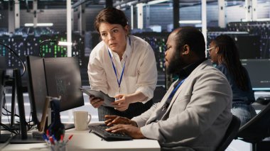 Sunucu odası yöneticisi, derin öğrenme algoritmalarını inceleyen teknisyenleri denetliyor. Veri Merkezi ekip lideri ve Afro-Amerikan çalışan denetimi Yapay Zeka ekipman platformlarının performans göstergesi, kamera A