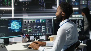 Donanımı yapılandırmak için yapay zeka sinir ağı modelleri kullanan veri merkezi yöneticisi. Adam sunucu odasında yapay zeka programlama dili üzerinde çalışıyor, sistem işlevselliğini optimize ediyor, kamera B