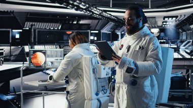 Astronot uzay istasyonu dışında planlanan operasyonlara katılmadan önce güvenlik kontrolü yapıyor. Kozmonot, Mars 'a indikten sonra ayrılmaya hazırlanan cihazdaki dişli kontrollerini kontrol ediyor.