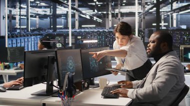 Sunucu odası yöneticisi, derin öğrenme algoritmalarını inceleyen teknisyenleri denetliyor. Veri Merkezi ekip lideri ve Afro-Amerikan çalışan denetimi Yapay Zeka ekipman platformlarının performans göstergesi, kamera A