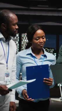 Proje stratejisi ve brifingde işbirliği yapan siyahi işçilerin dikey video portresi, performans ölçümlerini çalıştırmak için cihazların grafiklerindeki verileri kullanıyor. Ekip çalışması ve iş ortaklığı