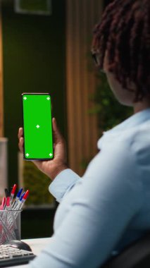 İşletme müdürüyle cep telefonundaki dikey video izole edilmiş krom anahtar, rapor yazma ve gece geç saatlerde veri analizlerini gözden geçirme üzerinde çalışıyor. Uzman inşaat iş stratejisi. Kamera.