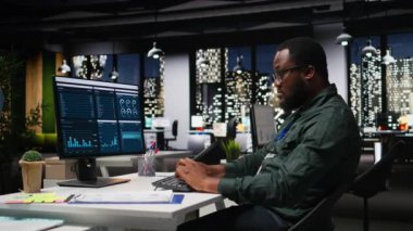 İş yönetimi için veri ve teknoloji kullanan erkek ofis çalışanı, raporlar oluşturmak ve verimliliği artırmak için monitördeki beyan grafiklerini gözden geçiriyor, hedeflere ulaşımı geliştiriyor. Vizyon. Kamera A.