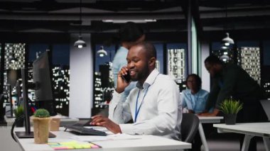 Afrika kökenli Amerikalı iş analisti gece geç saatlerde bir telefon görüşmesi yapıyor. Programın geleceğinden emin olmak için. Ortağıyla telefonda konuşuyor. Yönetici profesyonellik gösteriyor. Kamera A.