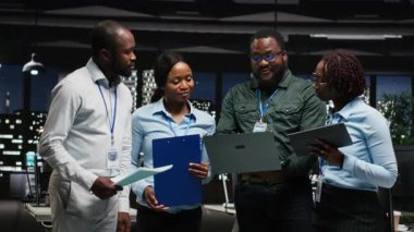 Proje stratejisi ve brifingde işbirliği yapan siyahi işçilerin portresi, performans ölçümlerini çalıştırmak için grafiklerdeki verileri kullanıyor. Ekip çalışması ve iş ortaklığı. Kamera B.