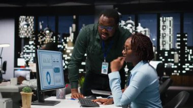 Siyahi iş arkadaşları masaüstü bilgisayarı ile ilgili veri içgörülerini analiz ediyor, şirket faaliyetleri için yeni bir strateji geliştirmeden önce analiz tahminine danışıyorlar. Kamera B.