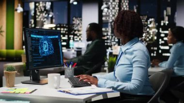 Siyahi kadın uzman KPI raporlarını bilgisayarda yapay zeka araçlarıyla inceleyerek yapay zeka ağlarıyla makine öğrenimi için çalışıyor. Yenilik ve optimizasyon vurgulanıyor. Kamera B.